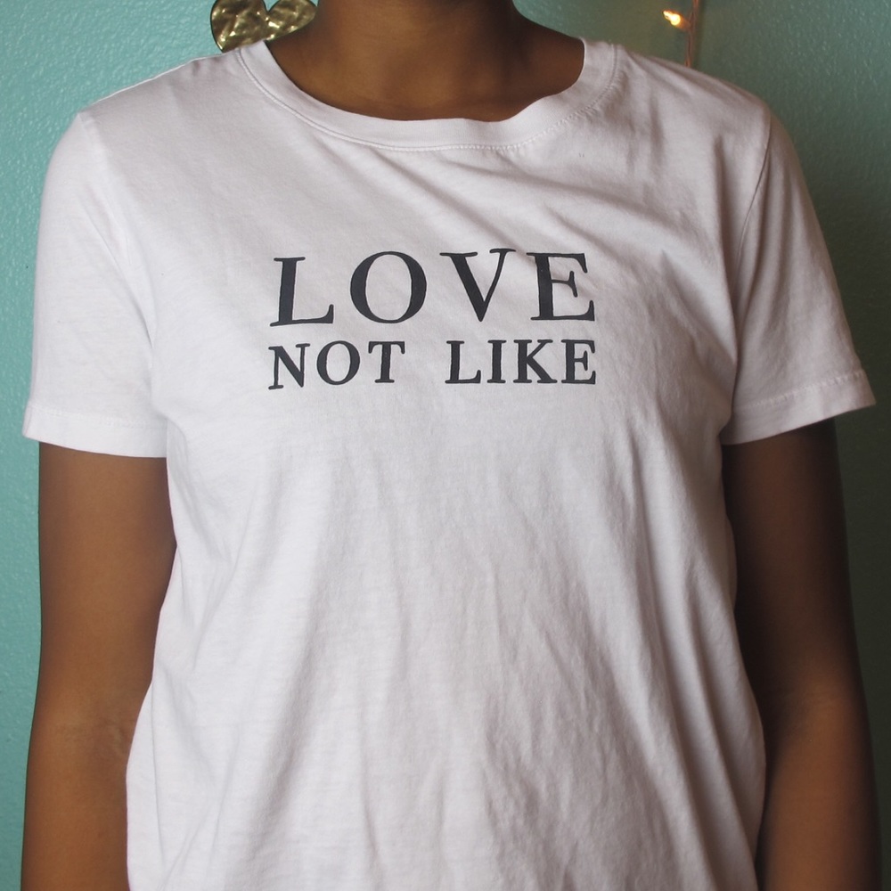 A white t-shirt that says Love Not Like in caps